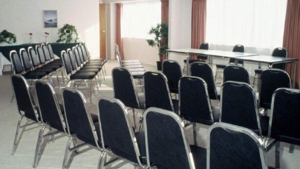 A conference room with rows of chairs, a long table, and large windows with curtains. - Auckland Akl Airport Motel (Auckland)