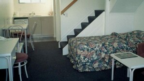 A compact room with a bed, a small table, a chair, and a staircase. - Auckland Akl Airport Motel (Auckland)