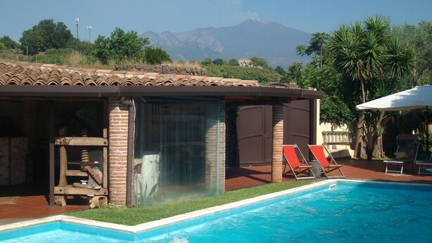 Un área de piscina con vistas a la montaña, una zona de estar cubierta y una sombrilla junto a la piscina.