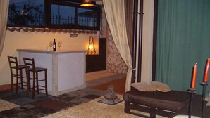 Una habitación acogedora con pared de piedra, una pequeña zona de bar y un área de estar con un banco y sillas.