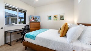 Ein Schlafzimmer mit Bett, Schreibtisch und Kommode. An der Wand hängen drei gerahmte Bilder.