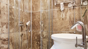 A modern bathroom with a glass-enclosed shower, a white sink, and a marble-tiled wall. - Lux Studio (Belgrade)