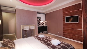 A modern hotel room with a bed, a desk, and a television. - Lux Studio (Belgrade)