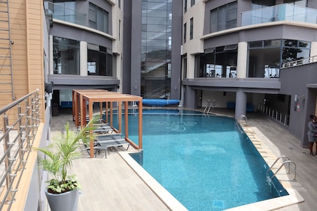 Una piscina al aire libre, sillones reclinables de piscina