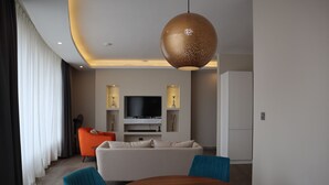 Ein modernes Wohnzimmer mit einem runden Holztisch, einem großen orangefarbenen Sofa und einem weißen Couchen.