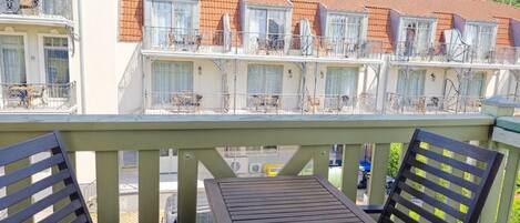 Ein Balkon mit Tisch und Stühlen, der auf eine Reihe von Reihenhäusern mit Balkonen blickt.