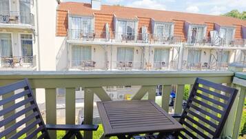 A balcony with a table and chairs, overlooking a row of terraced houses with balconies.