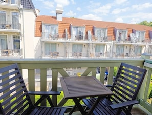 Un balcón con una mesa y sillas, con vistas a una hilera de casas escalonadas con balcones.