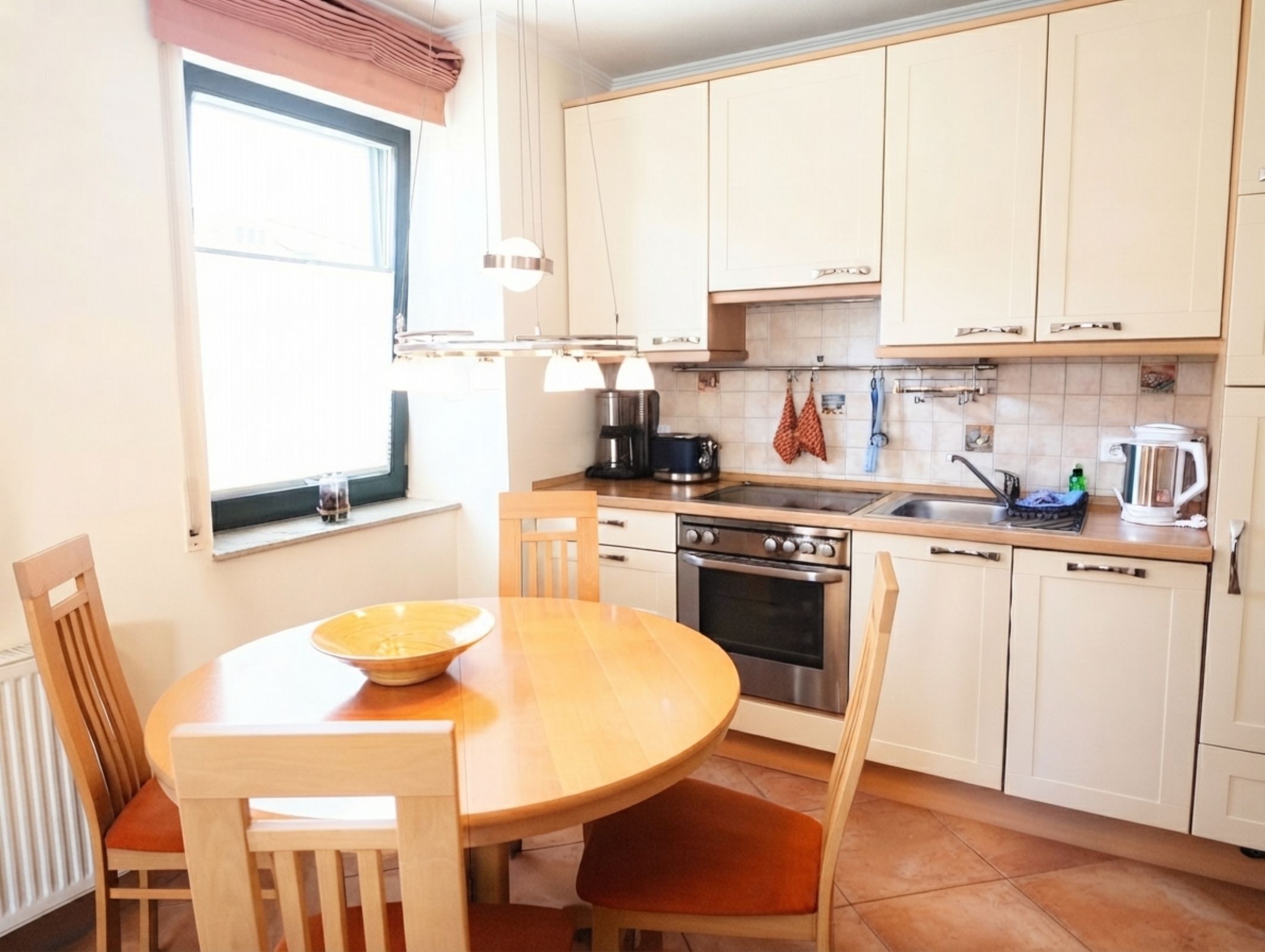 A kitchen with a wooden table, chairs, a stove, and cabinets.