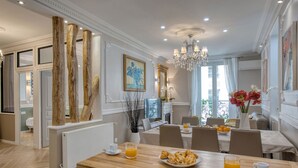 Un coin repas avec une table en bois, des chaises et des aliments pour le petit-déjeuner, comme des croissants et du jus d’orange.