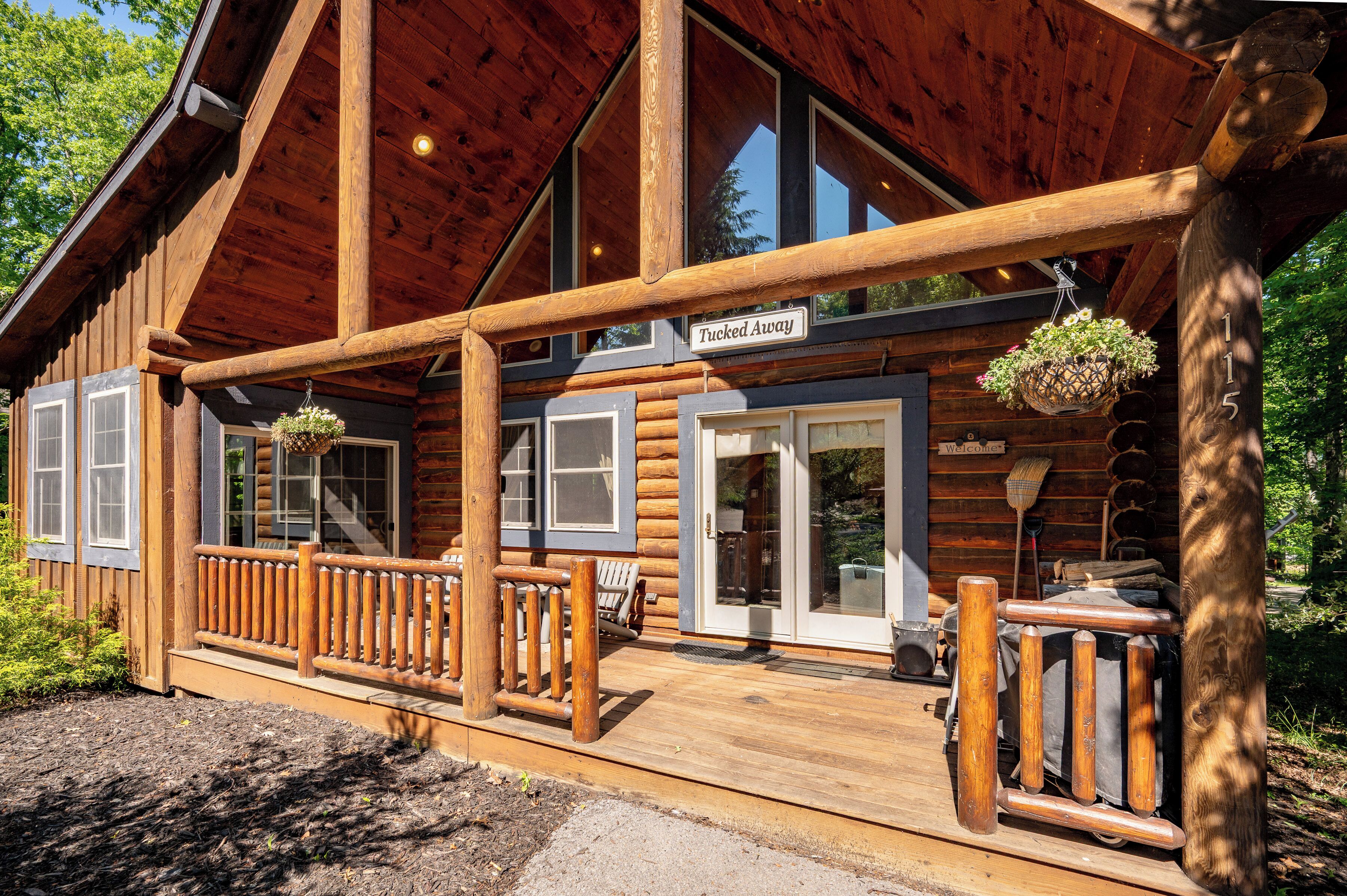 A log cabin with a porch, a welcome sign, and a 'Tucked Away' sign.