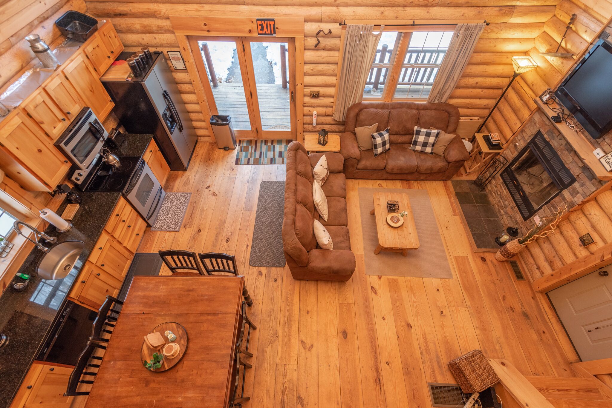A log cabin interior with a kitchen, dining area, and living room.