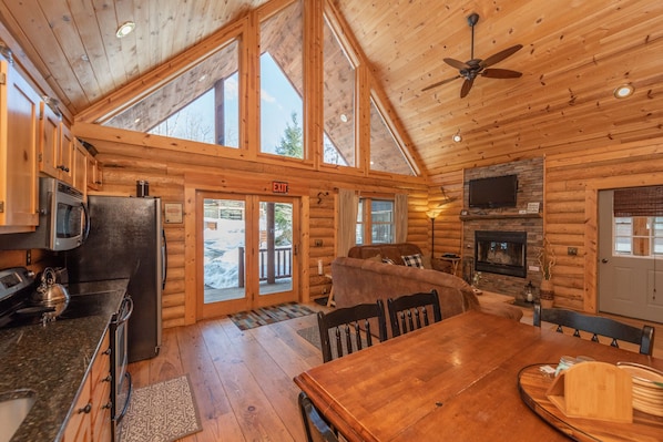 L’intérieur d’une cabane en rondins comprend une cuisine, un coin repas et une cheminée.