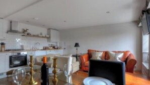 Una cocina moderna con armarios blancos y un comedor con una mesa preparada para dos.