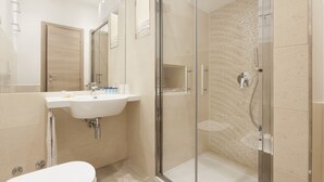A modern bathroom with a glass-enclosed shower, a sink with a mirror, and a toilet.