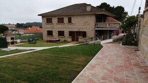Una casa de dos pisos con balcón, un pequeño jardín y un camino empedrado.