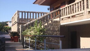 Una escalera de piedra que lleva a un edificio con balcones, plantas en macetas y cielo despejado.