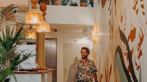 A hallway with a modern design, featuring a kitchen area with a white countertop and a sink, and a large wall with abstract art. - Palmito (Biarritz)