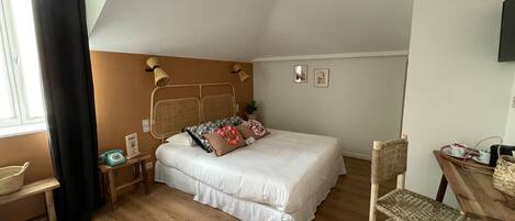 A bedroom with a bed, bedside tables, a chair, a small table, and a window with curtains.