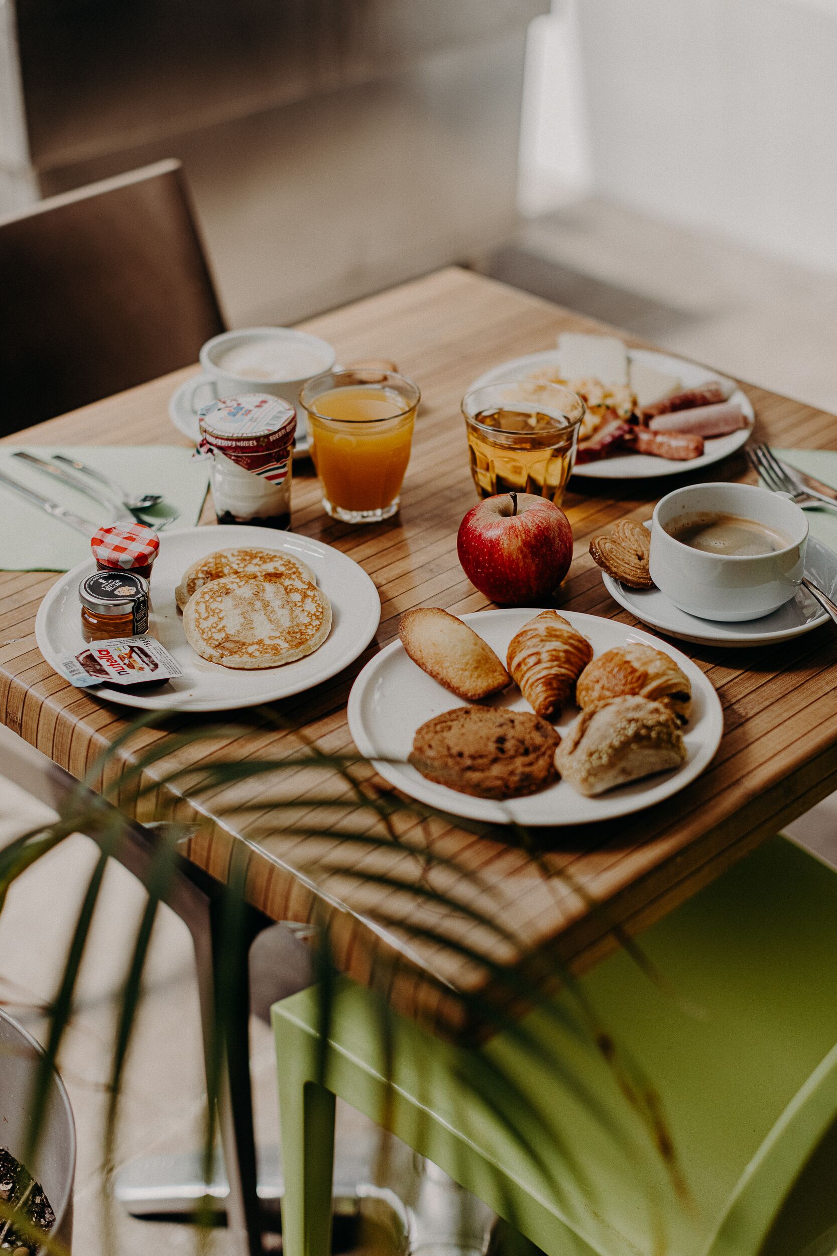 Una mesa de desayuno con platos de comida, un vaso de jugo de naranja, una taza de café y un frasco de mermelada.