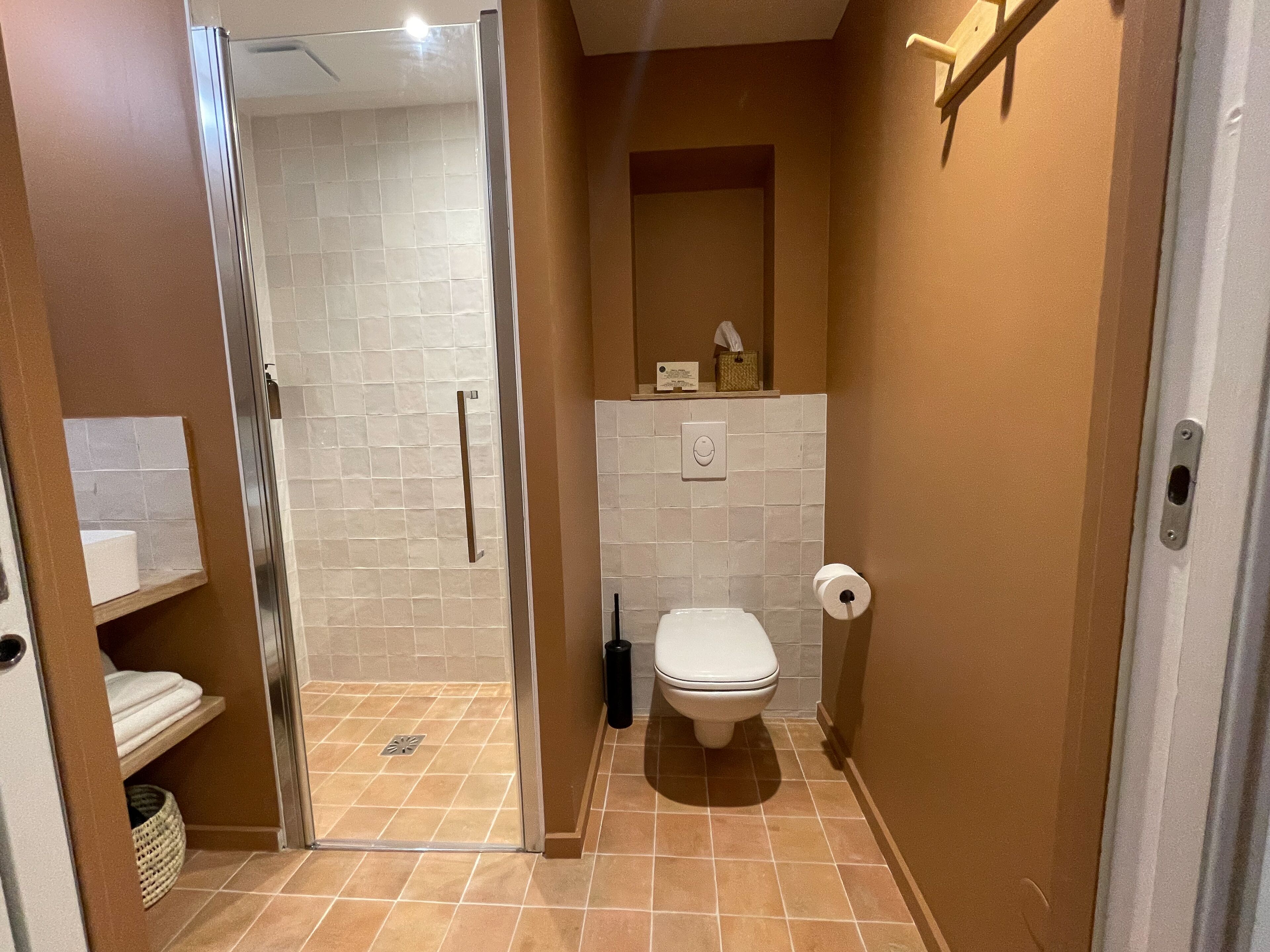 A bathroom with a shower, toilet, and a towel rack.