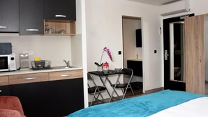 Une chambre d’hôtel moderne dotée d’une kitchenette, d’un coin repas et d’une salle de bain séparée.