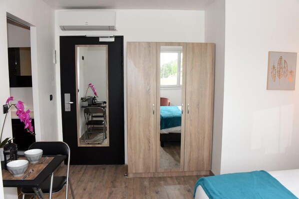 A bedroom with a bed, a wardrobe, a desk with a chair, and a small table with a bowl. - HOME PLACE (Langon)
