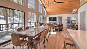 Un'ampia zona giorno con soffitto in legno, ampie finestre e un tavolo da pranzo con sedie.