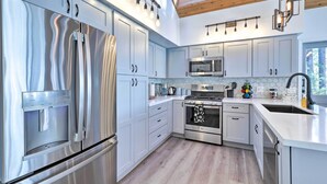 Una cucina moderna con elettrodomestici in acciaio inox, mobili bianchi e un lucernario.