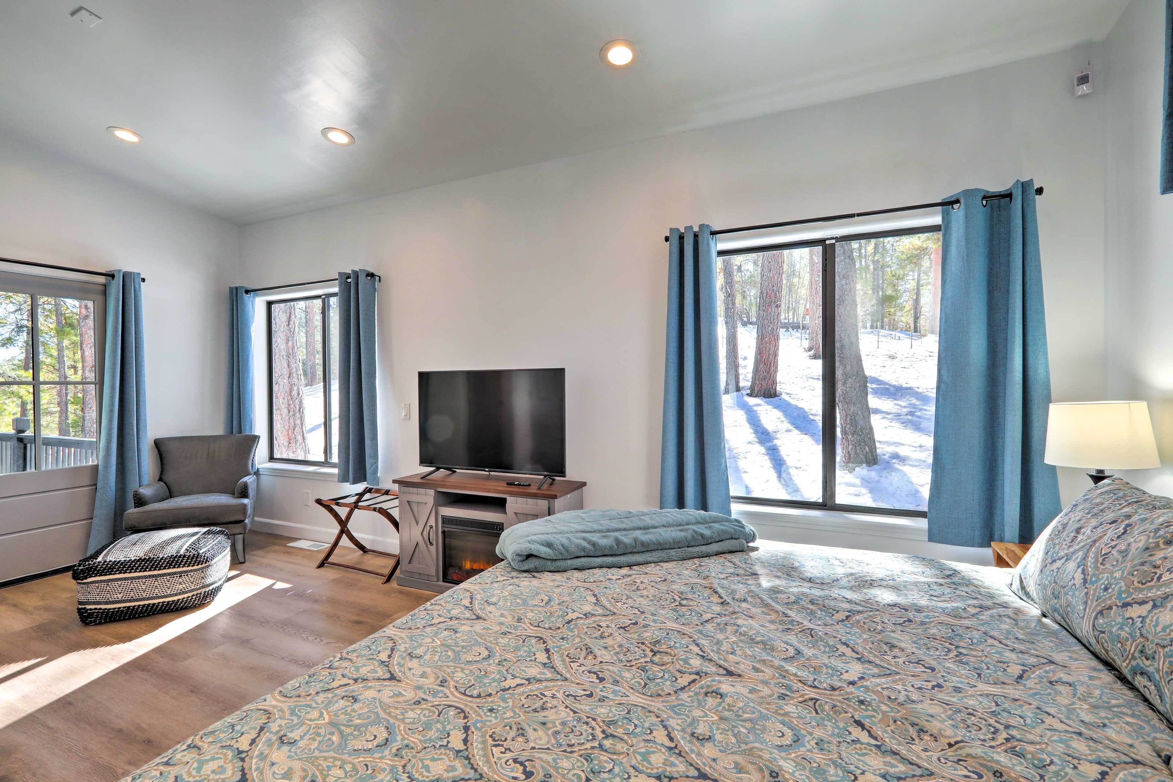 A spacious bedroom with a large bed, a TV, and a fireplace.