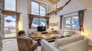 Un salón acogedor con un ventanal grande, un televisor de pantalla plana y una chimenea.