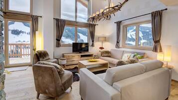 Ein gemütliches Wohnzimmer mit großem Fenster, Flachbildfernseher und Kamin.