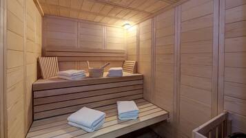 Eine Sauna mit Holzbänken, Stufen, Handtüchern und einer Lampe.