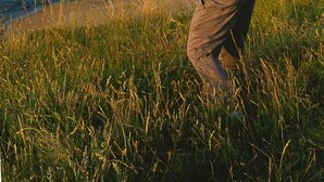 Une personne jouant au golf sur un parcours côtier, avec vue sur l’océan et un affleurement rocheux au loin.