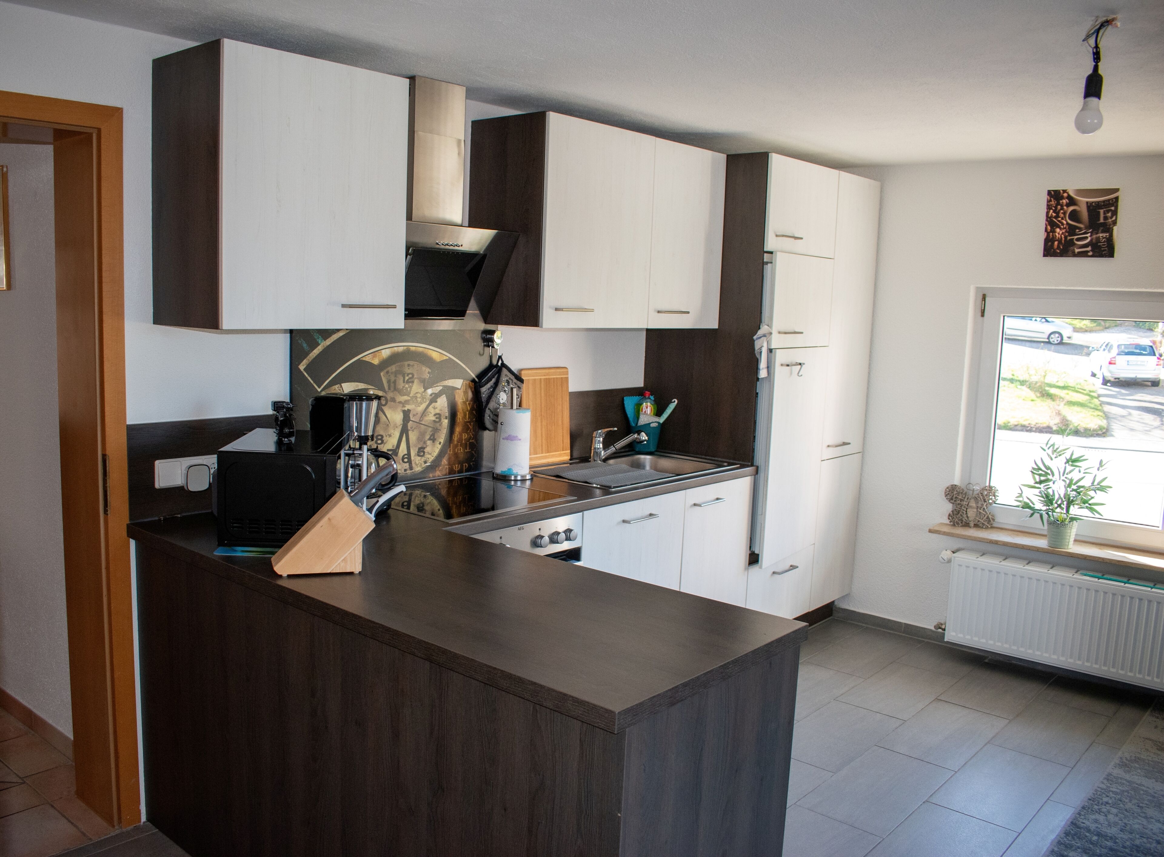 A modern kitchen with a central island, stainless steel appliances, and a window with a view of the street.