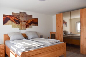 Ein Schlafzimmer mit einem hölzernen Bett, einem großen Spiegel und einem Wandbild mit Händen.