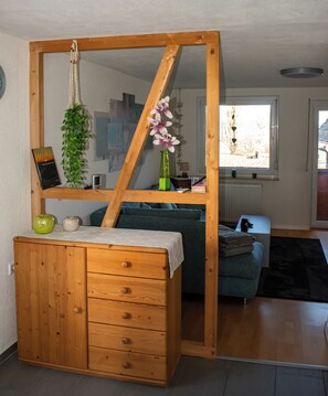 Ein Zimmer mit Schreibtisch aus Holz, einem grünen Blumenvasen, einem gerahmten Bild und einem Fenster mit Blick.