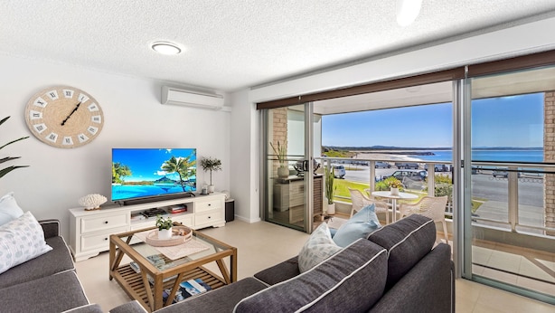 A modern living room with a TV, sofa, coffee table, and a balcony with a view of the sea. - Waves on North - El Sandi 4 (Forster)