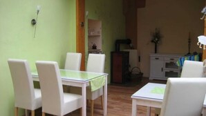 Zona pranzo con tavolo in vetro, sedie bianche, un mobiletto in legno e una piccola pianta.