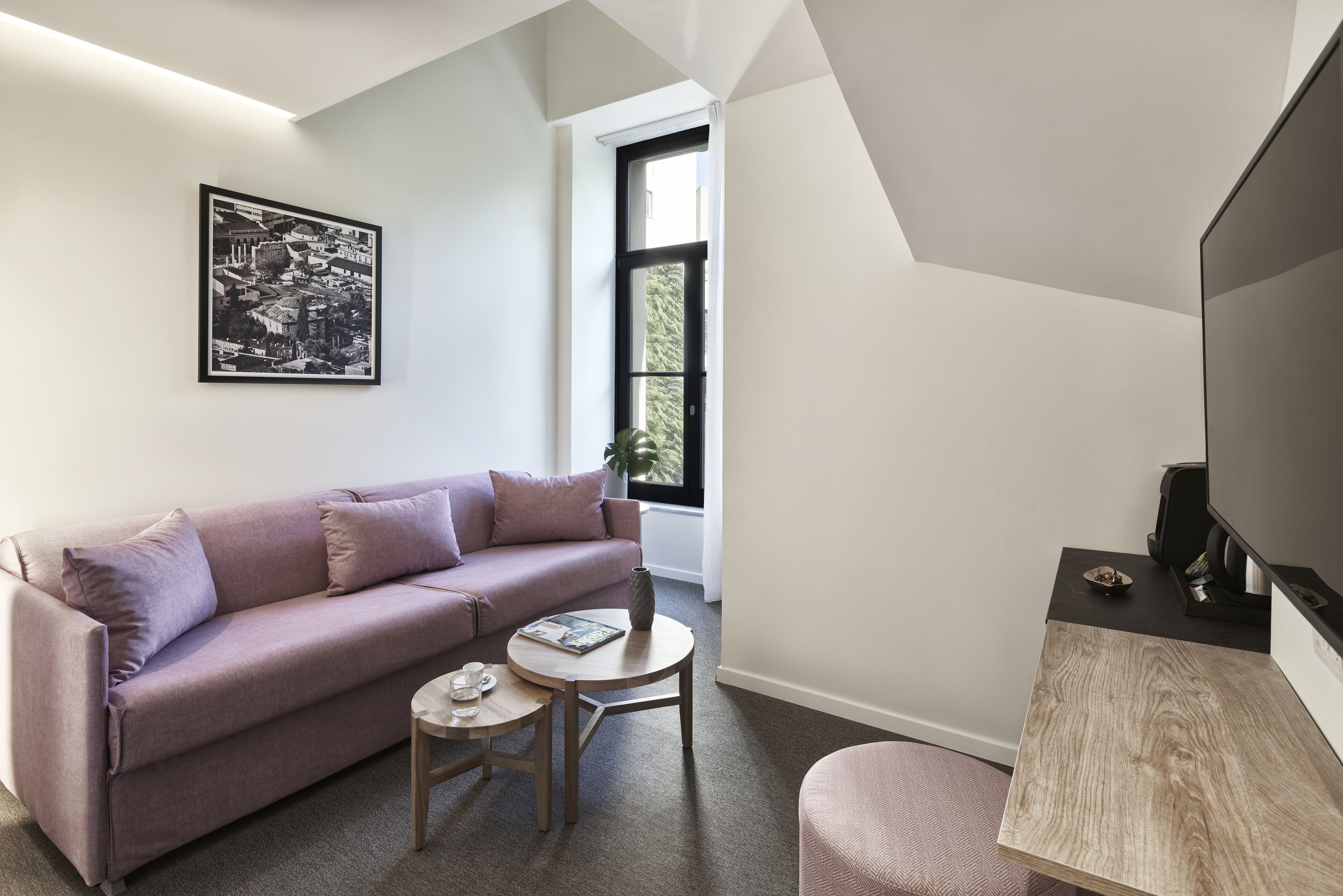 A modern living room with a sofa, a small round table, a coffee table, and a television.