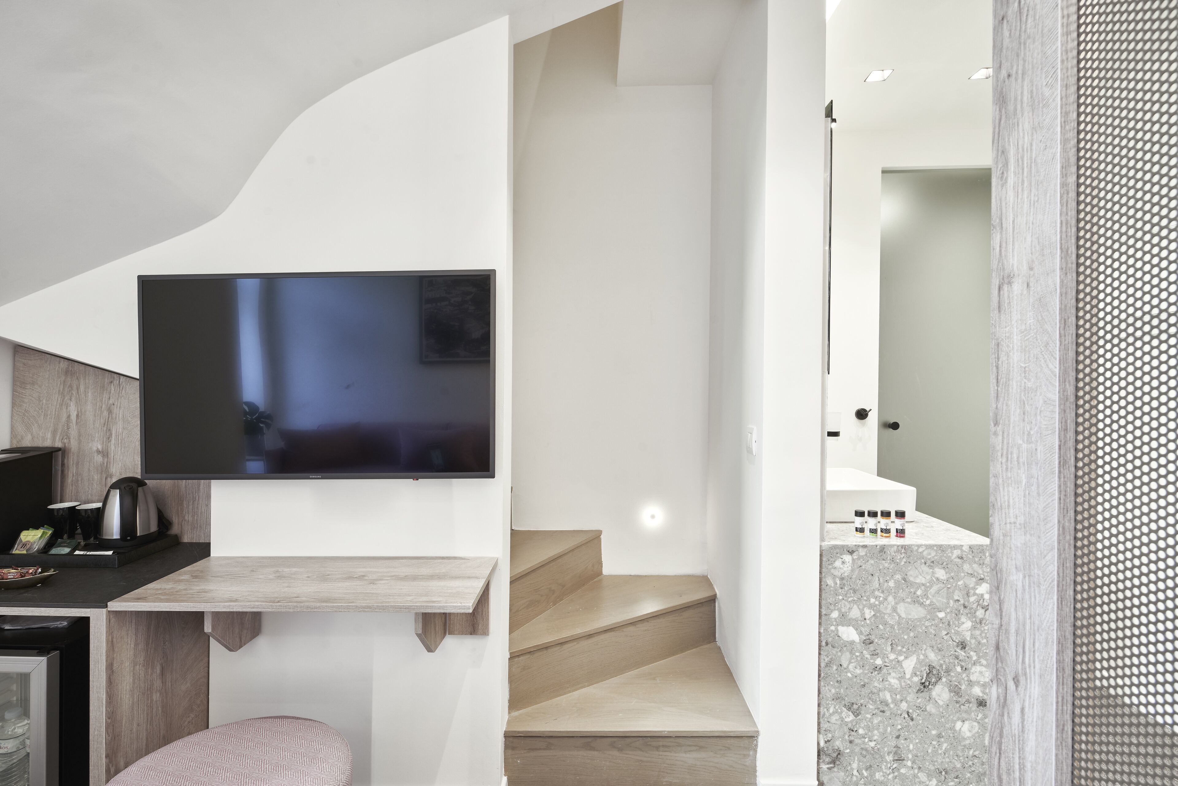 Une cuisine moderne dotée d’un téléviseur à écran plat, d’un comptoir en bois et d’un escalier menant à une salle de bain avec un espace douche.
