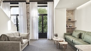 Un salon moderne avec un mur d’accent en pierre, un canapé vert, un canapé beige et une petite table en bois.