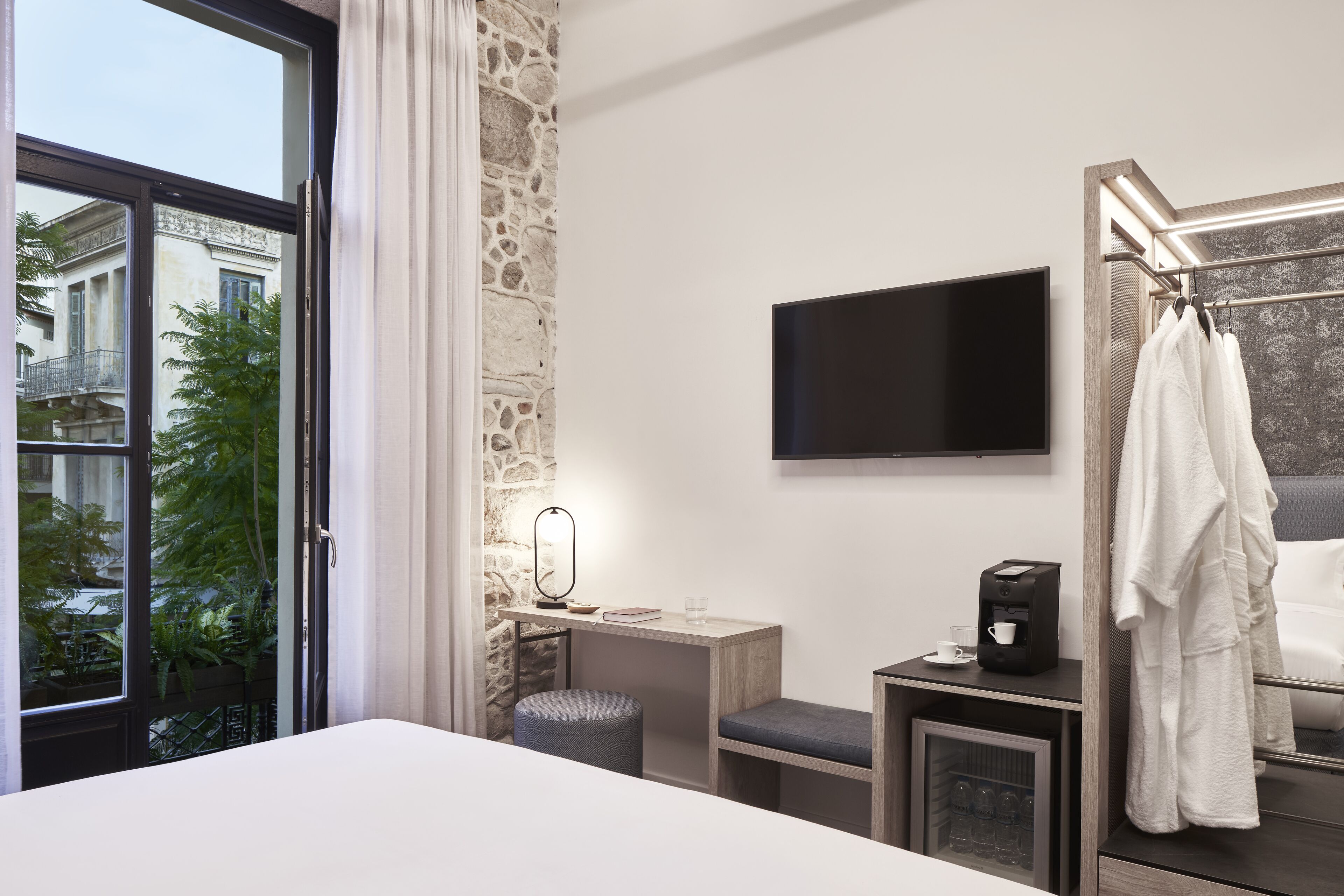 Une chambre d’hôtel avec un grand lit, un bureau avec une lampe, une télévision et une salle de bain équipée d’une baignoire et d’un peignoir.