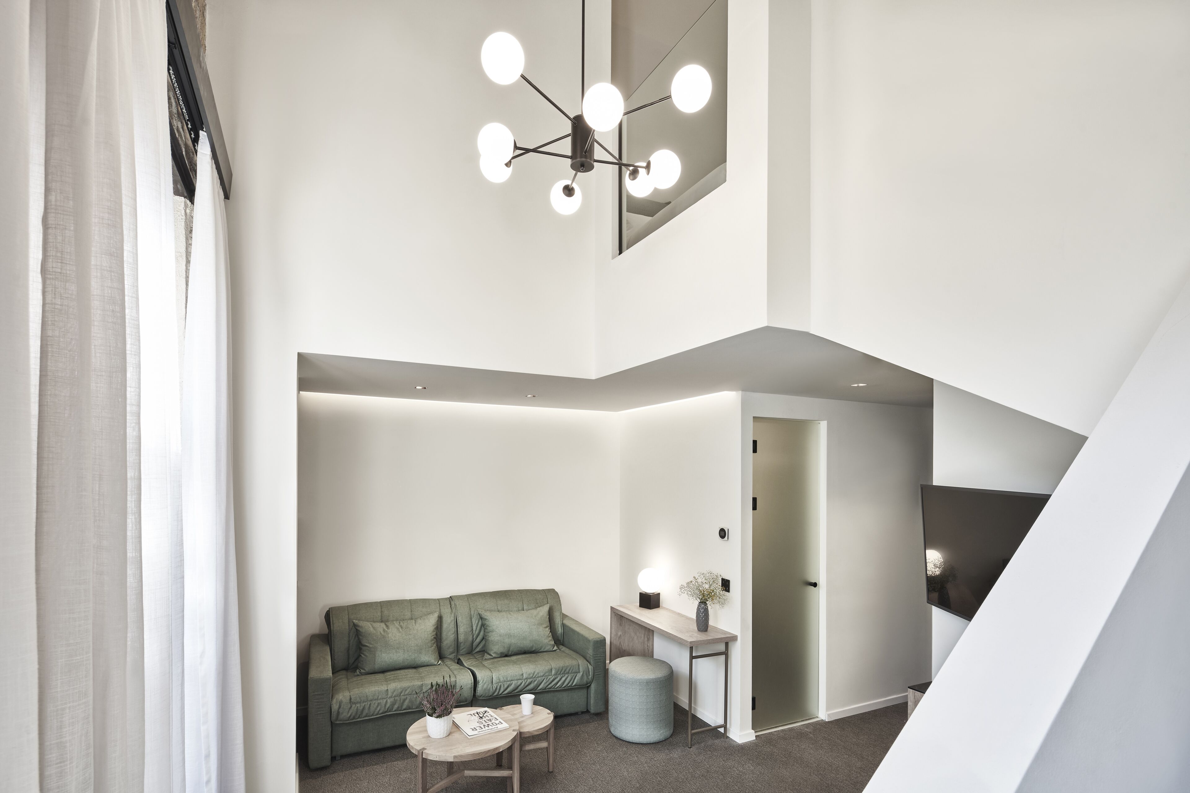A modern living room with a green sofa, a small table, and a unique ceiling light fixture.