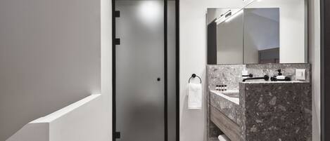 A modern bathroom with a wooden floor, a marble sink, and a large mirror.