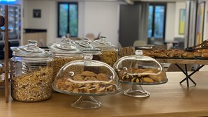 Une table de buffet proposant une variété de plats, notamment des bocaux de céréales et des plats couverts contenant des biscuits et des pâtisseries.