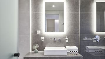 Un baño moderno con un lavamanos rectangular, un espejo grande y una zona de ducha.