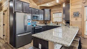Una cocina moderna con encimeras de granito, electrodomésticos de acero inoxidable y paneles de madera.
