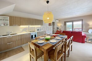 Una cocina moderna con armarios de madera, una mesa de comedor para cuatro personas y un sofá rojo en la sala de estar.