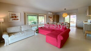 A spacious living room with a white sofa and a red sofa, a dining area with a table and chairs, and a kitchen area with a microwave and cabinets. - Exclusive villa with private pool (Santa Reparata)